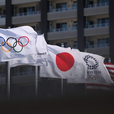 Olympic flags with the Olympic rings and Tokyo Olympics logo, as well as Japanese and American flags, are hoisted on flagpoles
