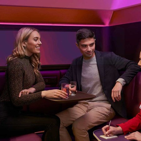 Two passengers on Virgin Atlantic ordering drinks in "The Booth," a new immersive social space on some A350 aircraft