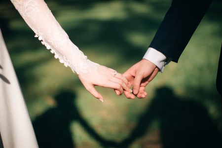 Photograph shows a bride and groom holding hands.