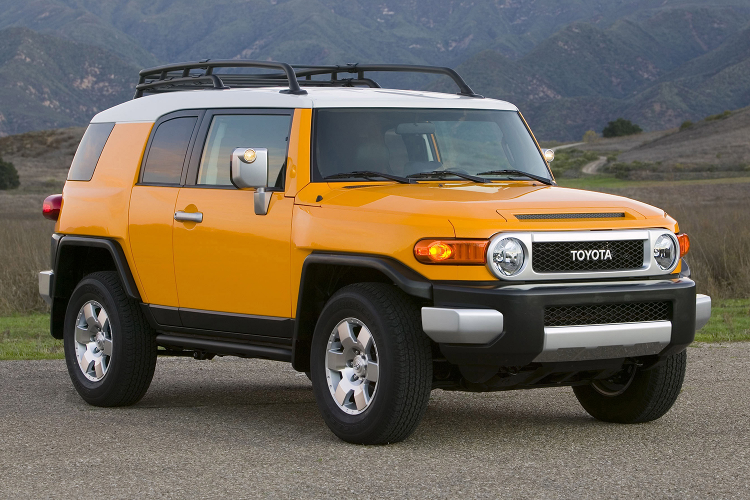 A yellow Toyota FJ Cruiser sitting still on the cement. The vintage off-road SUV was discontinued in 2014 but increasingly popular in 2021.