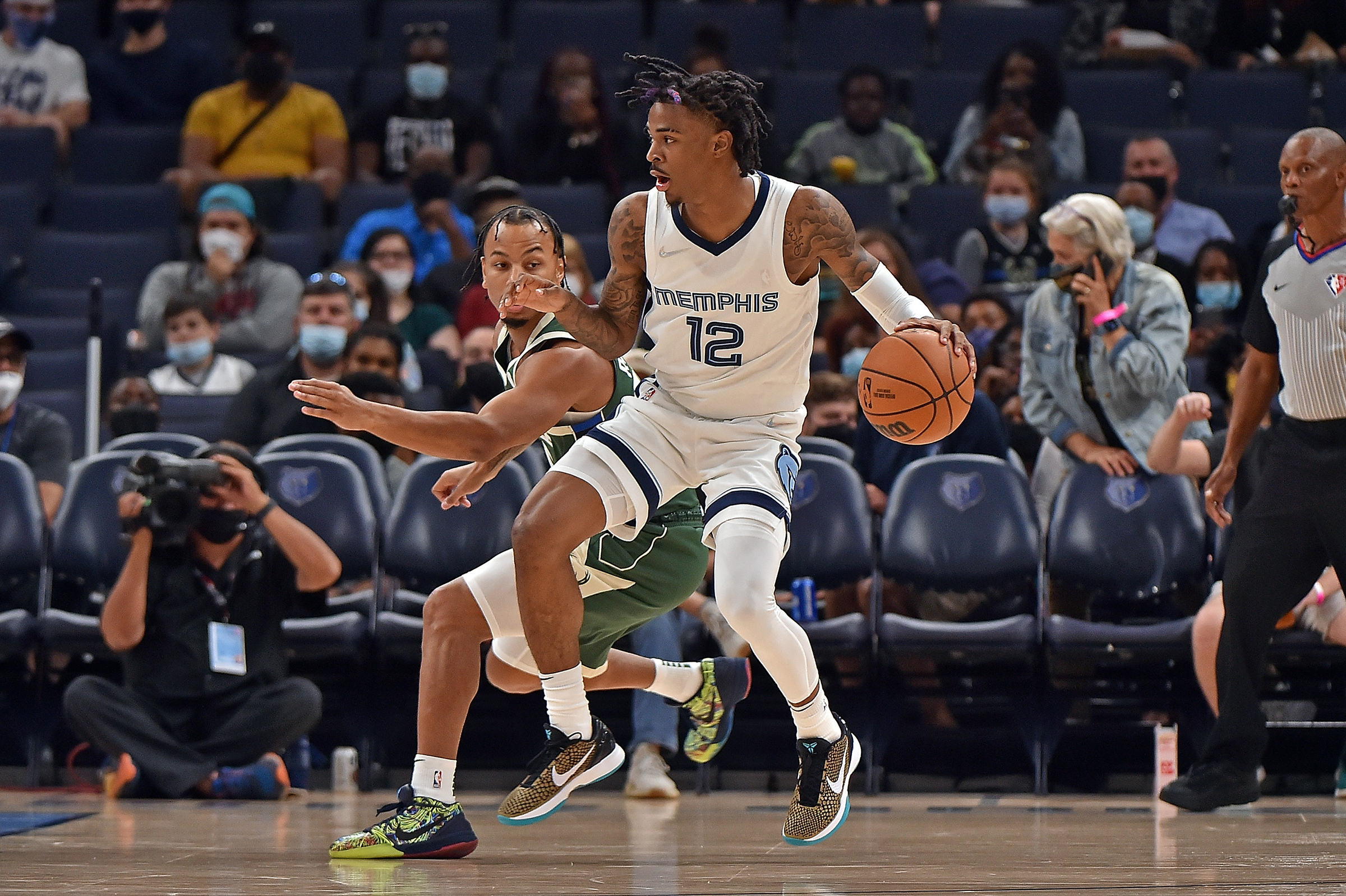 Ja Morant #12 of the Memphis Grizzlies handles the ball against Justin Robinson #55 of the Milwaukee Bucks during the first quarter during the preseason game at FedExForum on October 05, 2021 in Memphis, Tennessee. 
