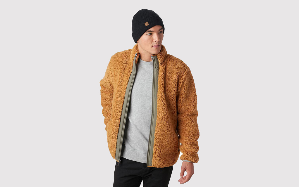 A man with a beanie wearing the Backcountry Sherwood Full-Zip Fleece jacket in an orange-brown color called bone brown