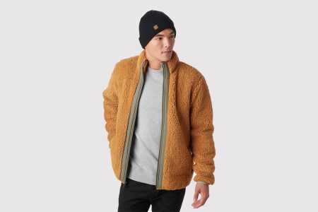 A man with a beanie wearing the Backcountry Sherwood Full-Zip Fleece jacket in an orange-brown color called bone brown