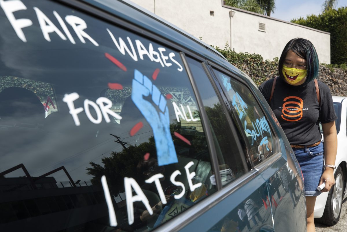 Crystal Kan, a storyboard artist, draws pro-labor signs on cars of union members during a rally at the Motion Picture Editors Guild IATSE Local 700 on Sunday, Sept. 26, 2021 in Los Angeles.