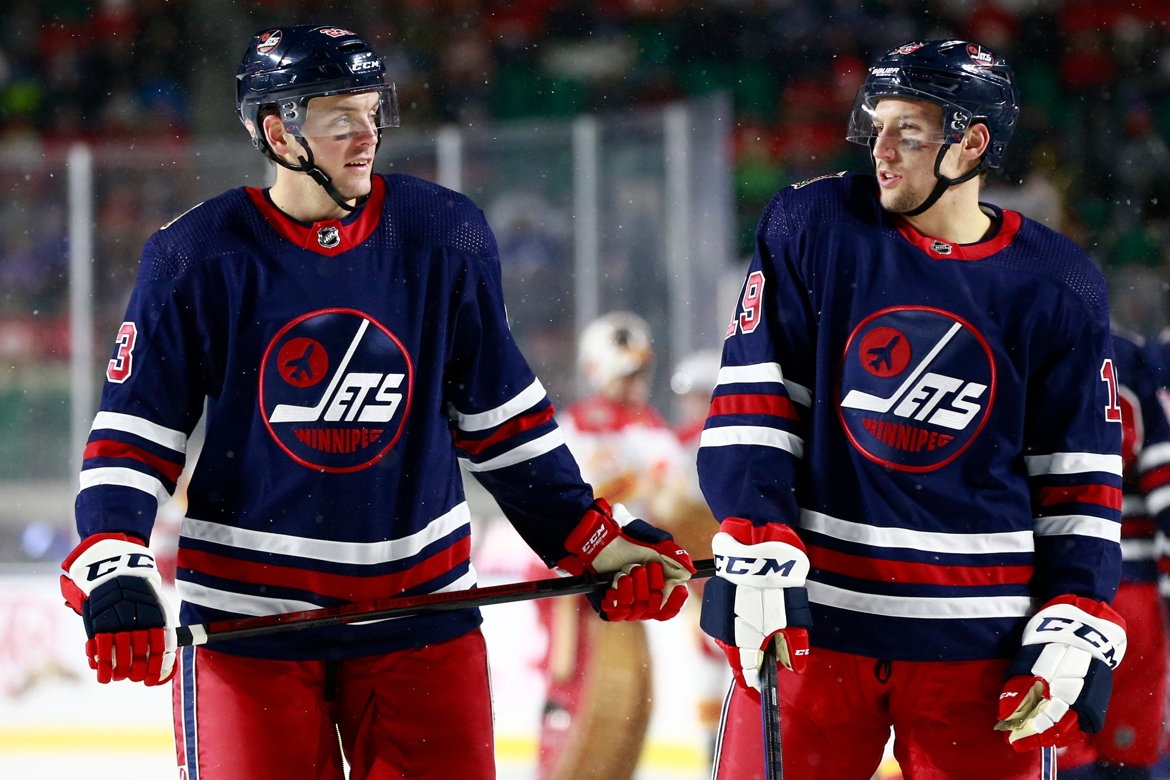 Carl Dahlstrom #23 (L) and David Gustafsson #19 of the Winnipeg Jets stand talk while playing in the 2019 Tim Hortons NHL Heritage Classic against the Calgary Flames at Mosaic Stadium on October 26, 2019 in Regina, Canada