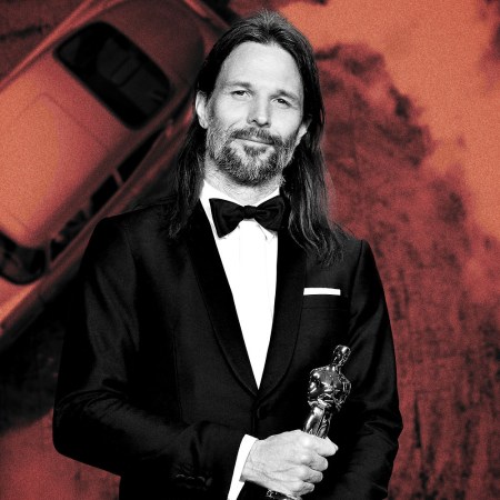 No Time to Die cinematographer Linus Sandgren holding the Oscar he won for La La Land, with James Bond's Aston Martin DB5 driving in the background