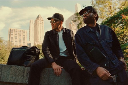 two men sitting on wall with Montblanc bags