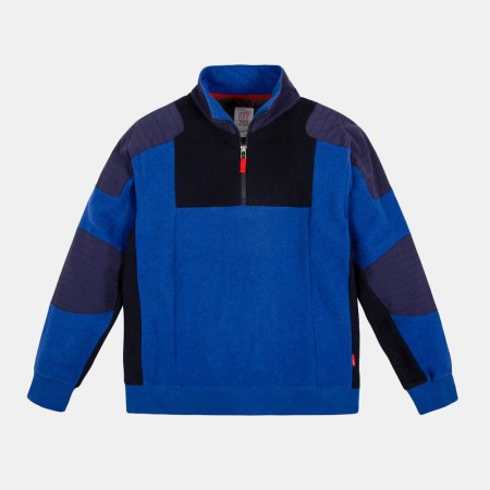 The Global 1/4 Zip Sweater from Topo Designs in blue and black on a grey background