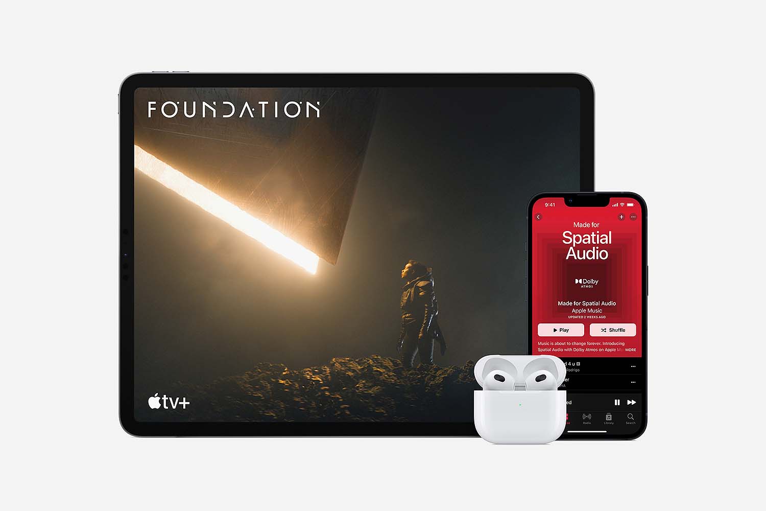 The third gen of AirPods, now with spatial audio, near an iPad and iPhone playing the Apple TV show "Foundation"