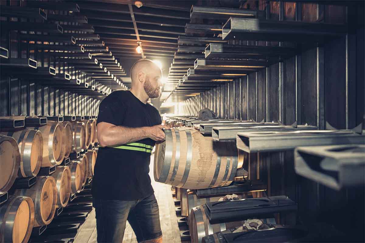 A man storing barrels on Barge 166. The 1948 Freycinet barge was completely restored and equipped by Maison Ferrand to house approximately 1,500 custom 30-liter barrels