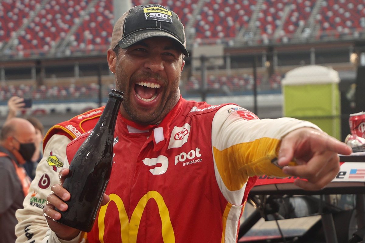 Bubba Wallace in red and yellow McDonald's branded livery celebrates after winning the rain-shortened NASCAR Cup Series YellaWood 500 at Talladega Superspeedway