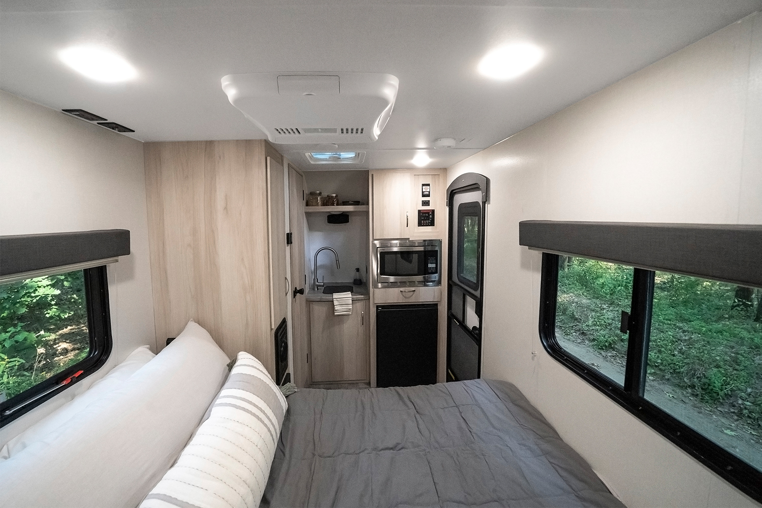 The interior of the new Winnebago Hike 100 small SUV travel trailer, featuring a bed, sink, microwave, refrigerator and wet bath