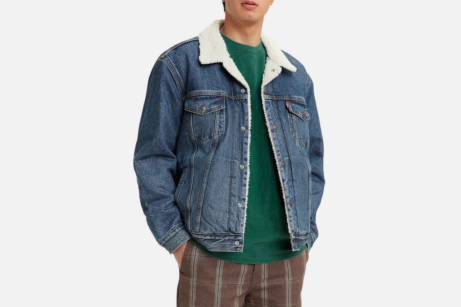 A man wearing a sherpa-lined trucker jacket from Levi's, done up in denim, with a green shirt