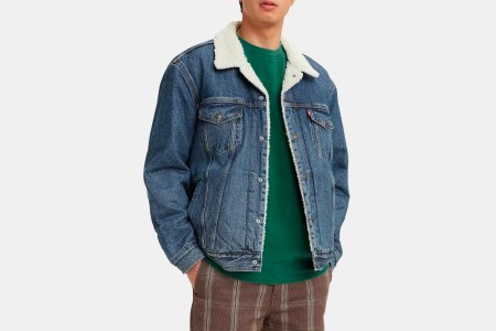 A man wearing a sherpa-lined trucker jacket from Levi's, done up in denim, with a green shirt