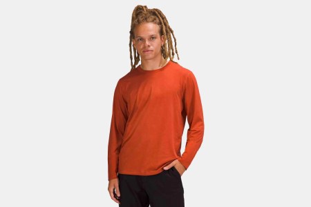 A man wearing Lululemon's Fundamental Long Sleeve workout shirt in orange