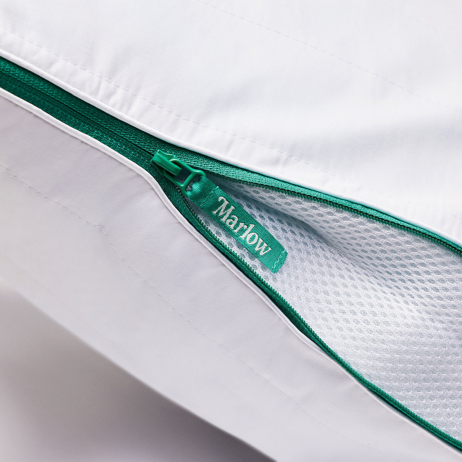 A Marlow pillow from Brooklinen's new sub-brand showing a close-up of the green zipper on the side that adjusts the pillow's firmness