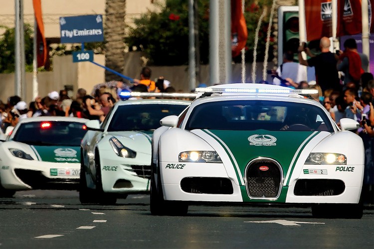 A United Arab Emirates police convoy driving down the street in Dubai featuring a Bugatti, Ferrari and McLaren police car