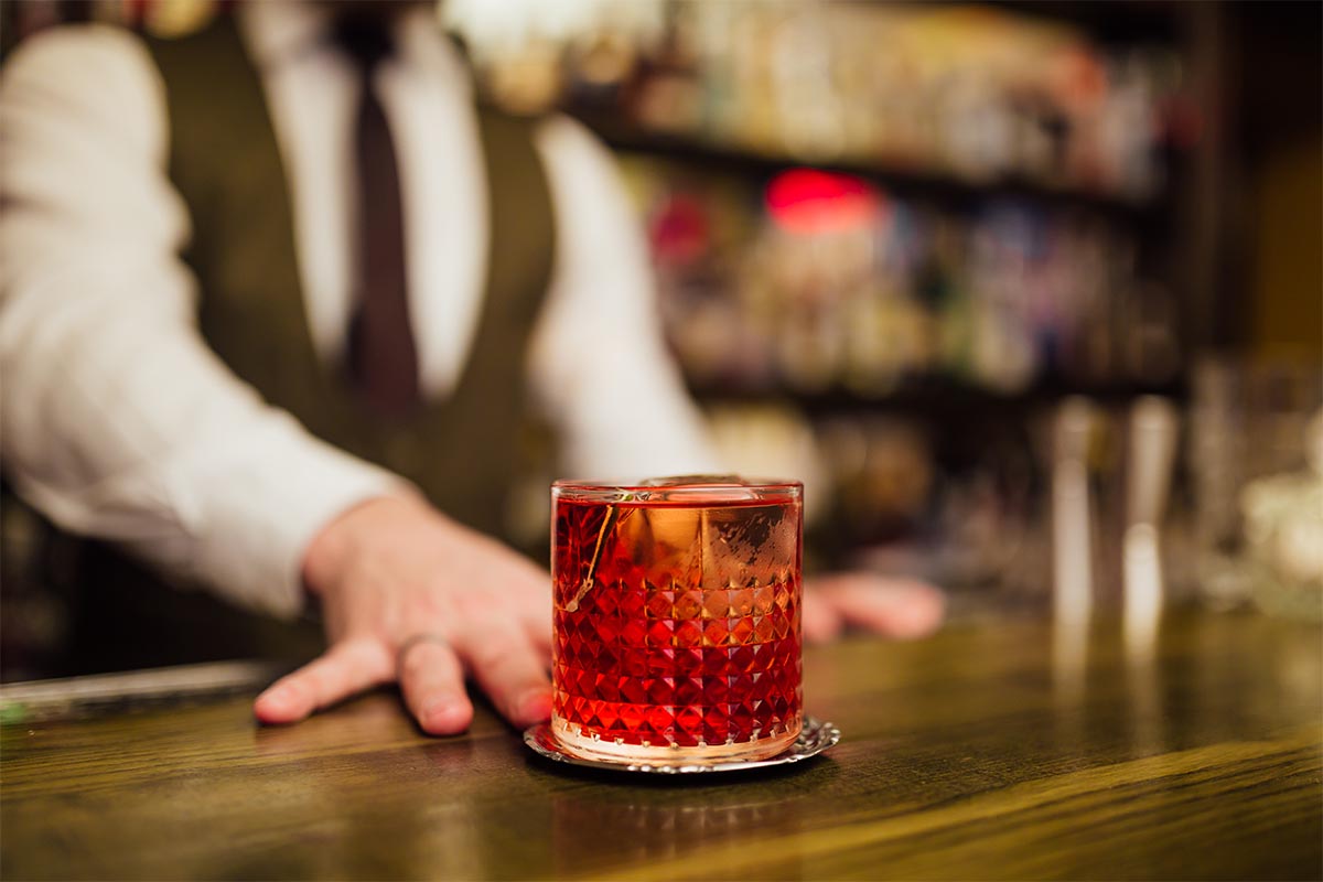 A bartender serving a single Negroni at a bar. Some bars specialize or focus on just one cocktail.