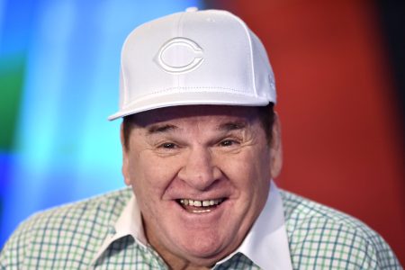 Pete Rose visits the Fox Business Network Studios wearing a white Cincinnati Reds hat and a green checker shirt with a white collar