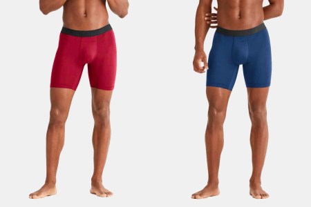 Two men shot from the torso down wearing Rhone's Essentials Active Boxer Briefs, the left in red and the right in blue
