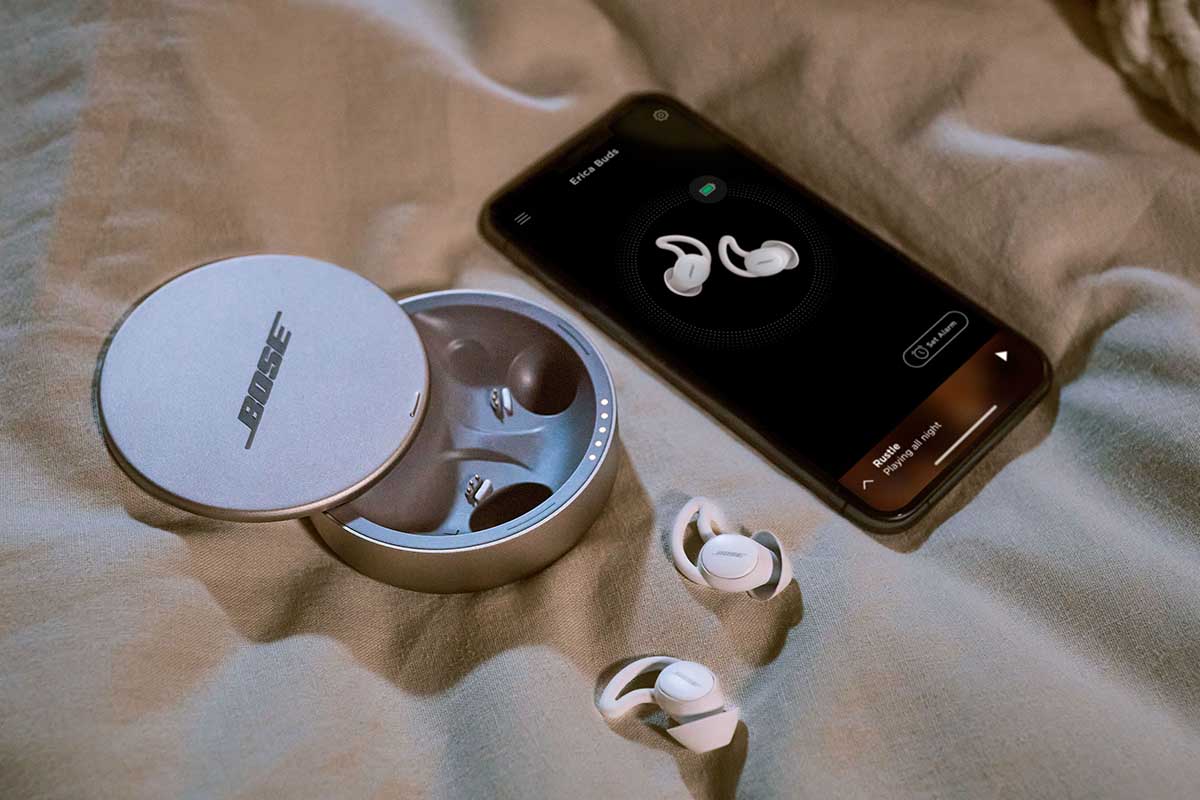 Bose Sleepbuds II out of their carrying case and with a phone that has the Bose app