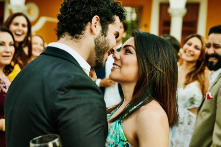 Smiling and embracing couple about to kiss during outdoor wedding reception. Tinder now offers a "plus one" service to bring dates to weddings.