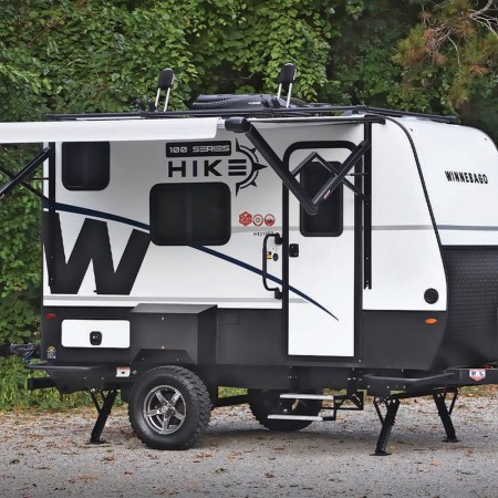 The new Hike 100 travel trailer from Winnebago sitting on a gravel plot in the woods
