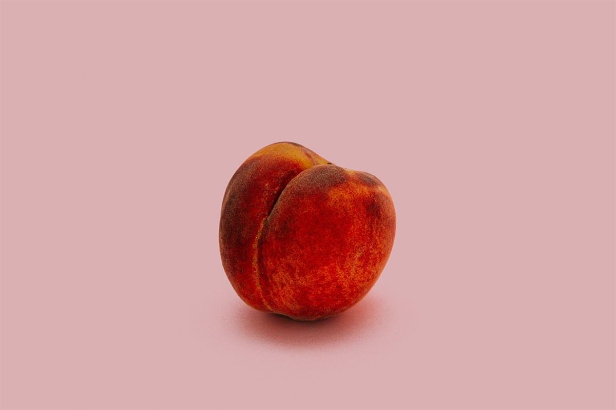 A peach against a pink background.