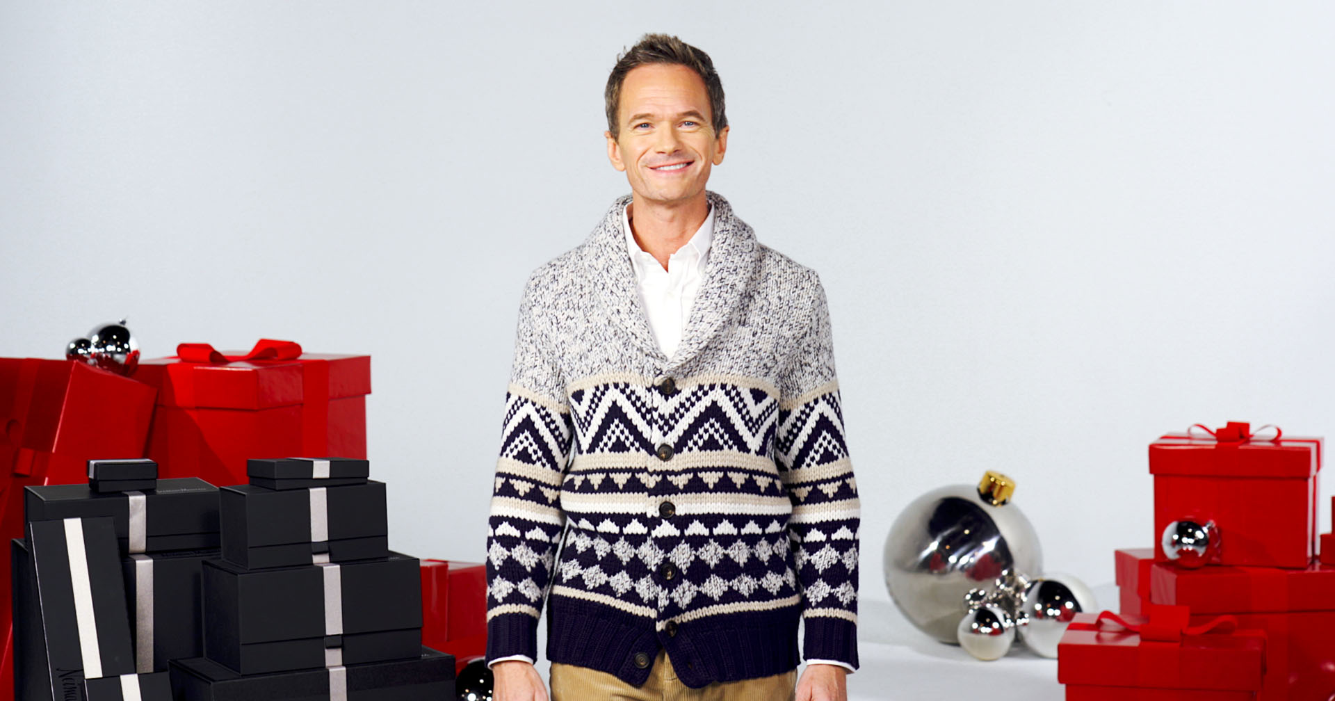 neil patrick harris surrounded by gift boxes wearing a cozy cardigan