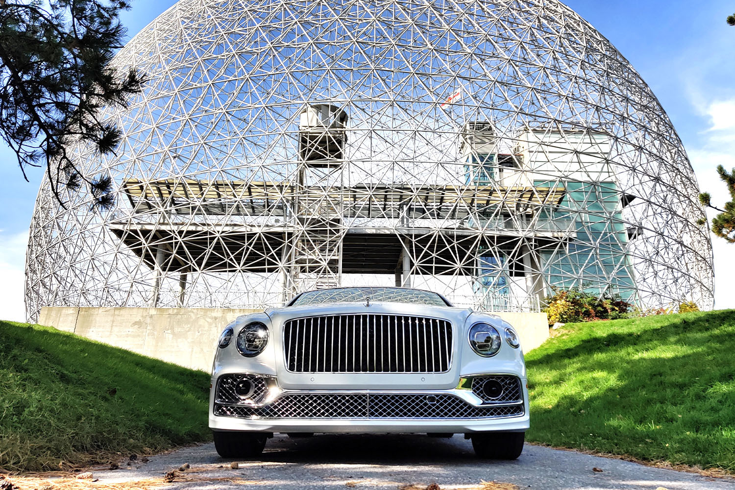 The 2022 Bentley Flying Spur in white in front of the Montreal Biosphere with a dome designed by Buckminster Fuller