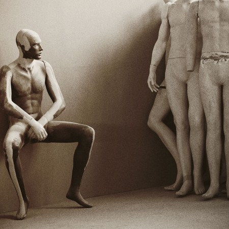 A nude mannequin sits gazing up at a group of other nude mannequins standing nearby