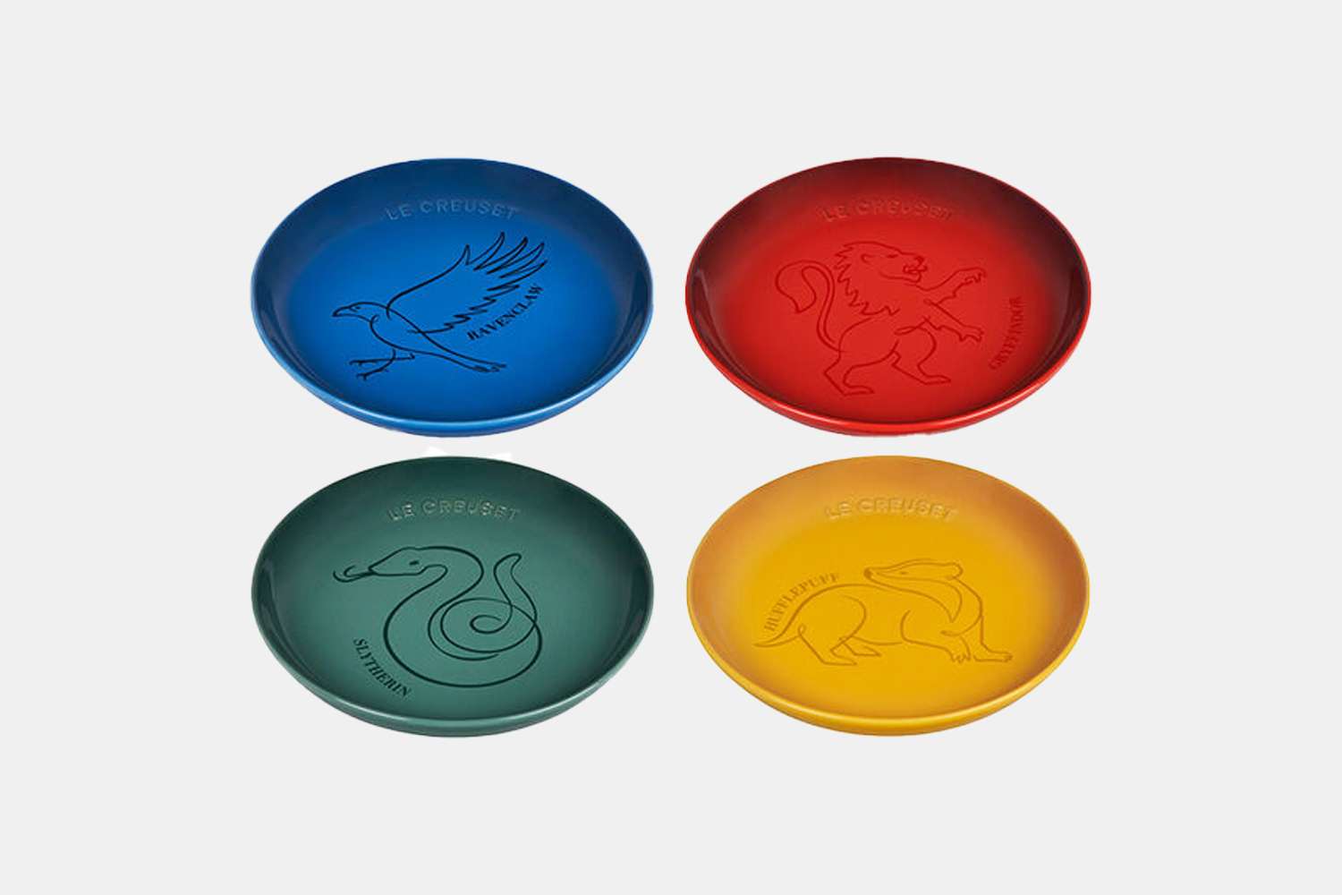A collection of four plates in different howgarts house colors