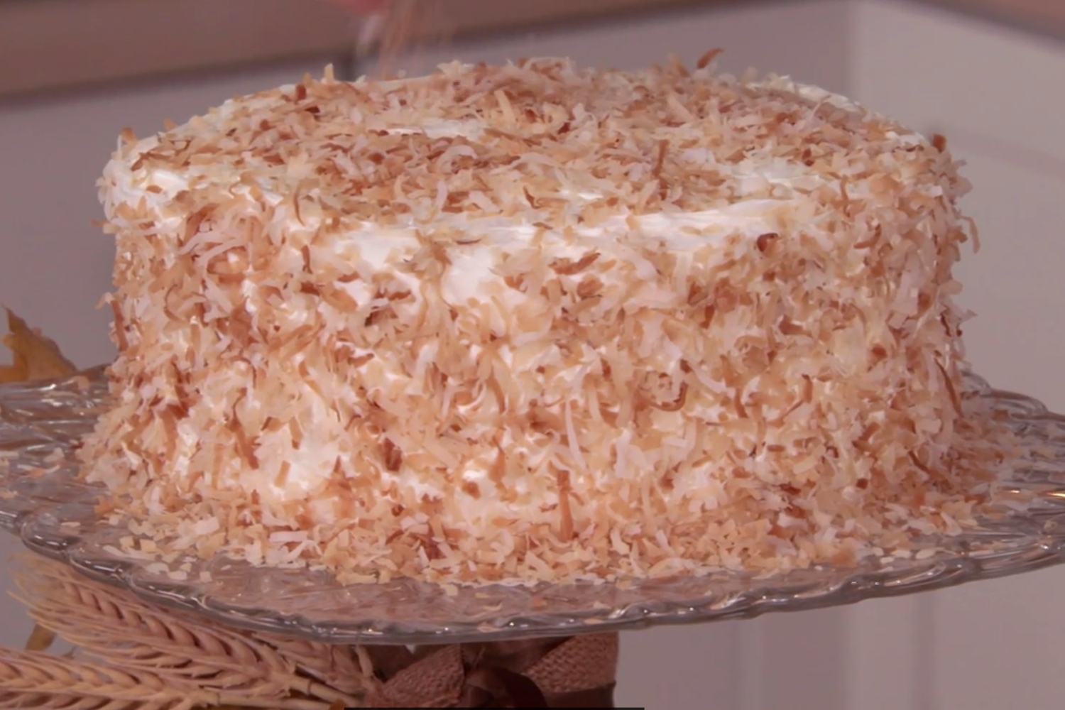 A white-frosted cake coated in toasted coconut flakes