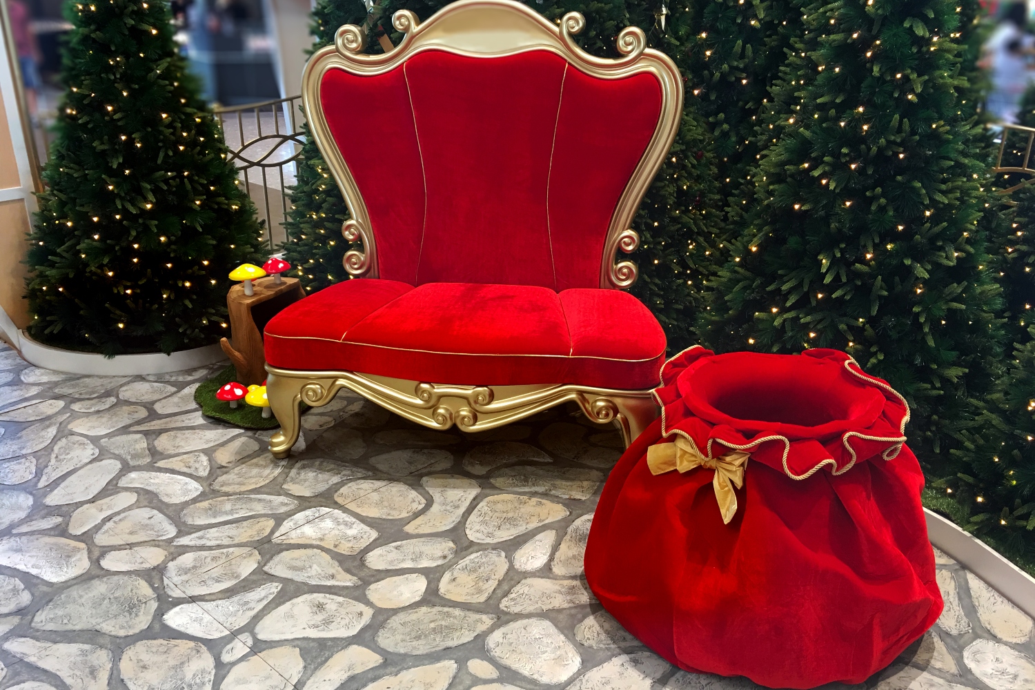 An empty red velvet Santa chair and red velvet bag