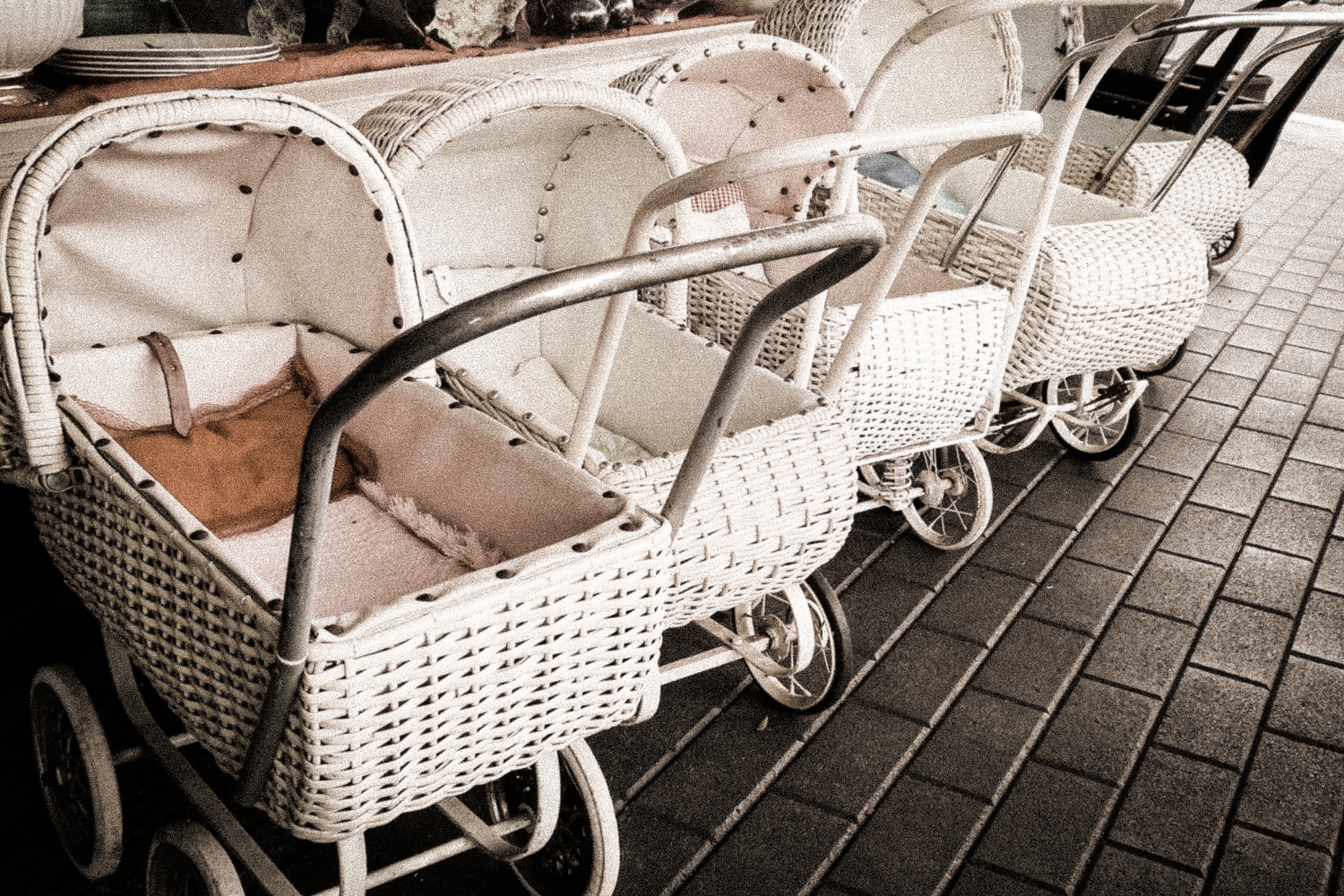 Photo shows row of white, empty baby carriages
