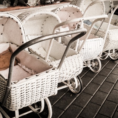 Photo shows row of white, empty baby carriages
