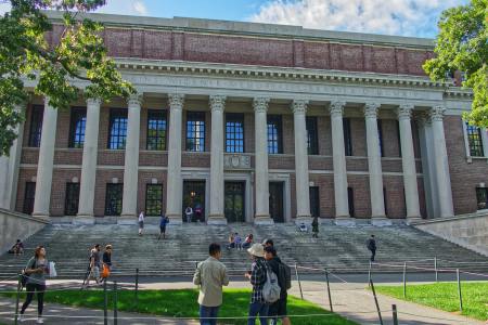 Students on the grass in front of and on the stairs of Widener Library at Harvard during the day
