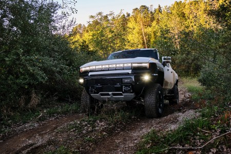 The GMC Hummer EV driving through mud in the woods as part of an engineering test for the electric supertruck