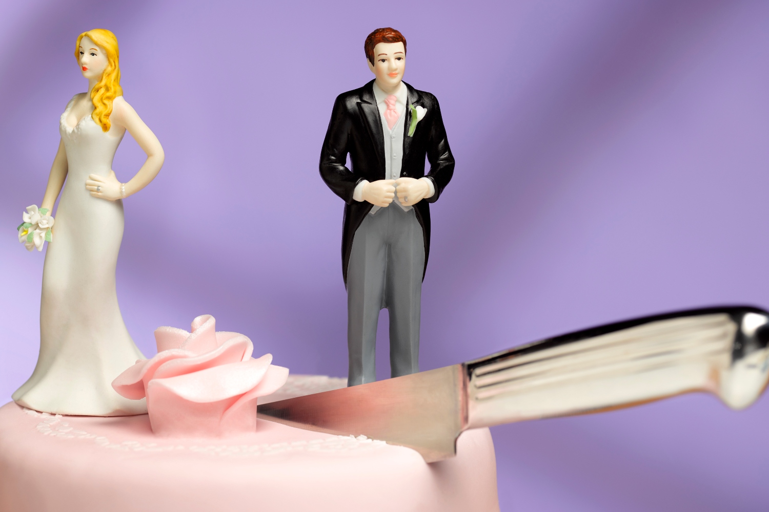 Bride and groom wedding cake toppers separated by knife; divorce concept