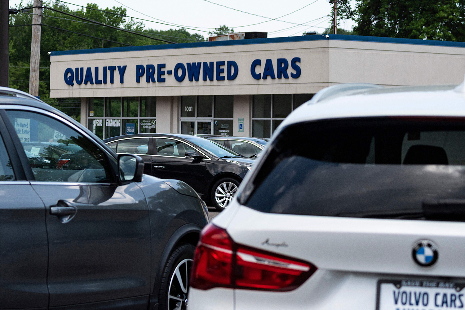 A white BMW seen in the foreground of a photo of a used car dealership lot in Annapolis, Maryland on May 27, 2021