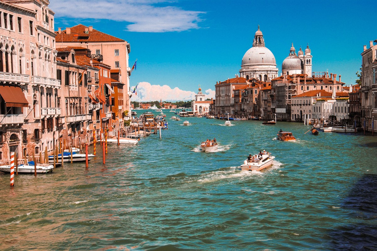 Gondolas glide along the waters of Venice's Grand Canal in summer