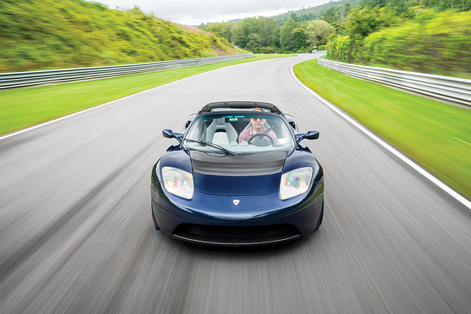 A 2010 Tesla Roadster Sport, one of the earliest electric cars from Elon Musk's Tesla, driving fast down a racetrack. The EV is on Hagerty's 2022 Bull Market List.