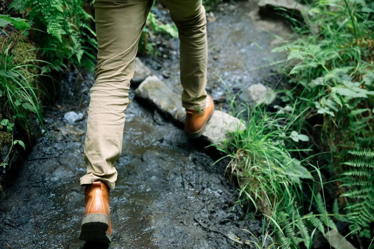 A model walking in Aether Apparel boots in a forest