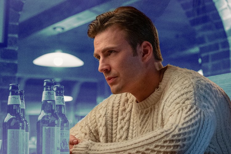 Chris Evans in the movie Knives Out wearing a white fisherman sweater on a blue toned background