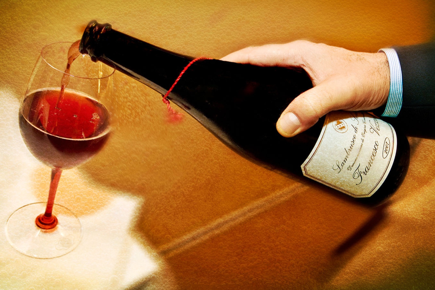 Photo shows a hand pouring a glass of red lambrusco