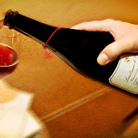 Photo shows a hand pouring a glass of red lambrusco