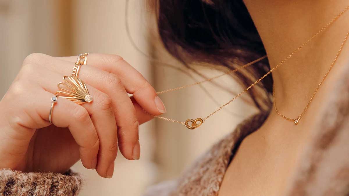 Gold ring, necklace and earrings from Aurate, on a gold and marble background