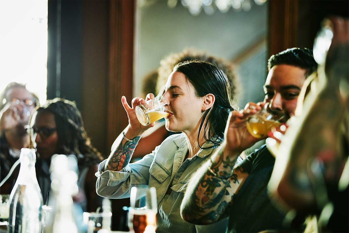 A stock photo of a woman enjoying drinks with some friends at a bar counter. Bacardi's new Trends Report suggests we'll be returning to bars and asking for some interesting new experiences when we do in 2022.