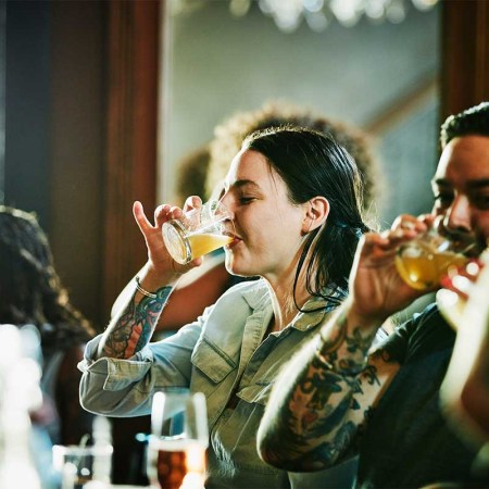 A stock photo of a woman enjoying drinks with some friends at a bar counter. Bacardi's new Trends Report suggests we'll be returning to bars and asking for some interesting new experiences when we do in 2022.
