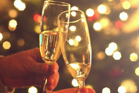 Close-up photo shows hands raising two glasses of champagne for a toast